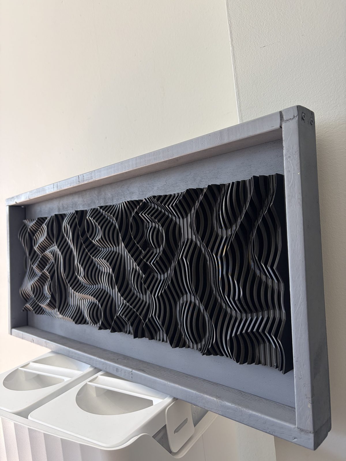Close-up of parametric wave wall art showing precise layered fins